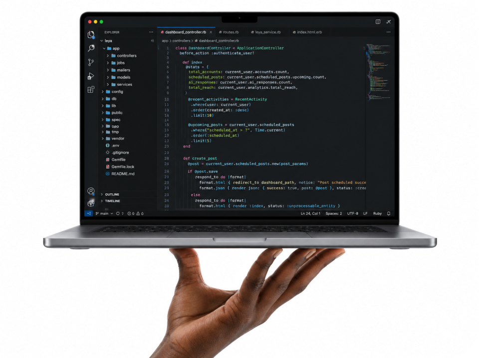 A hand holding an open laptop showing Ruby application code